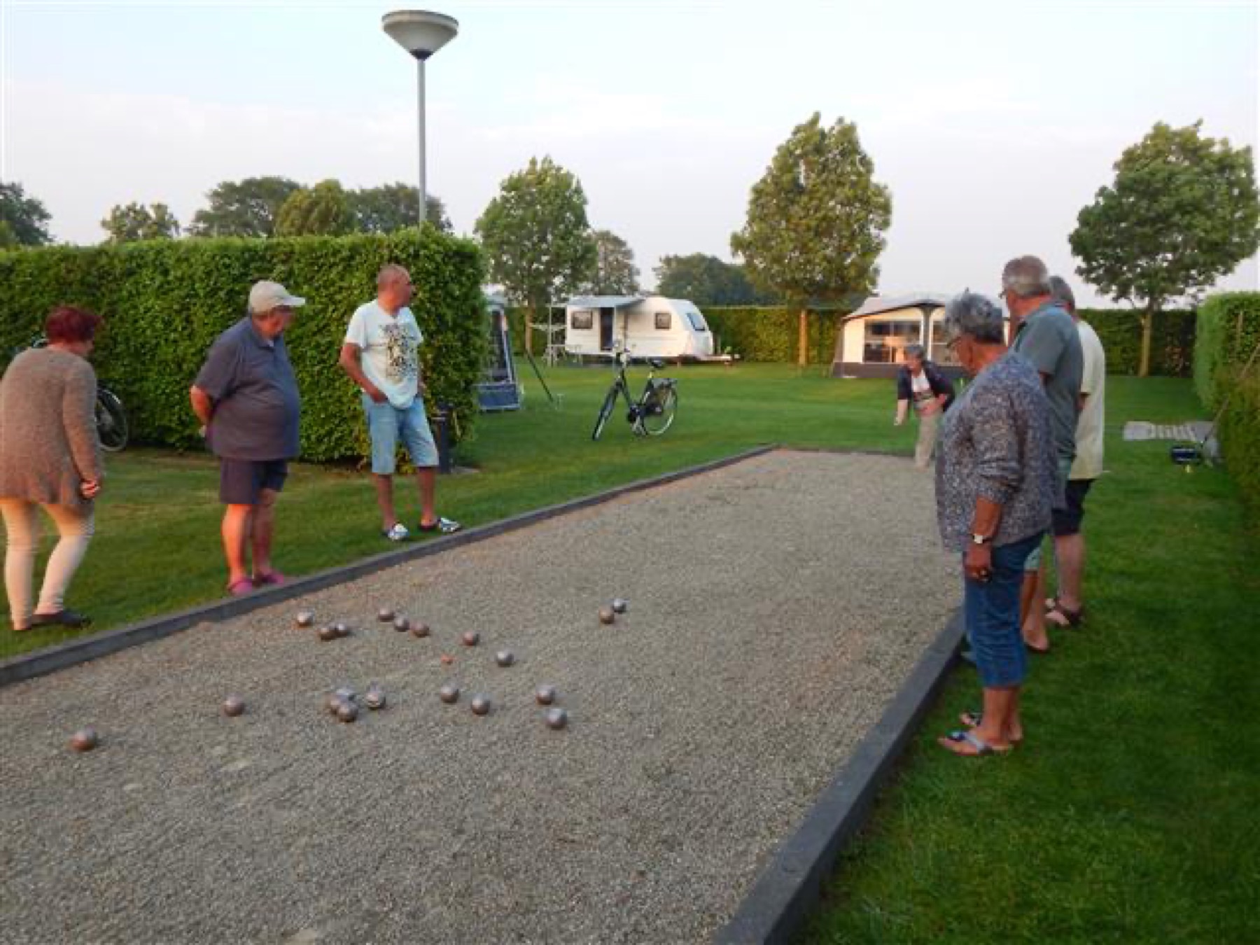 Gasten spelen jeu de boules op de baan naast het veld